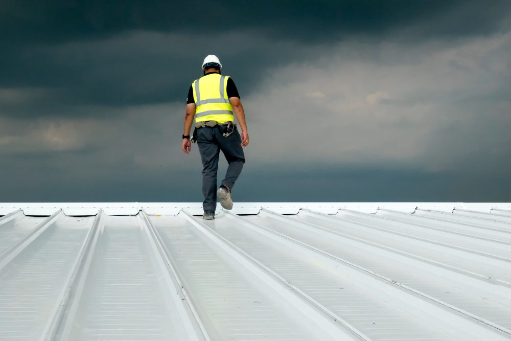 A commercial roofing contractor inspecting a flat roof on a Tulsa business property.