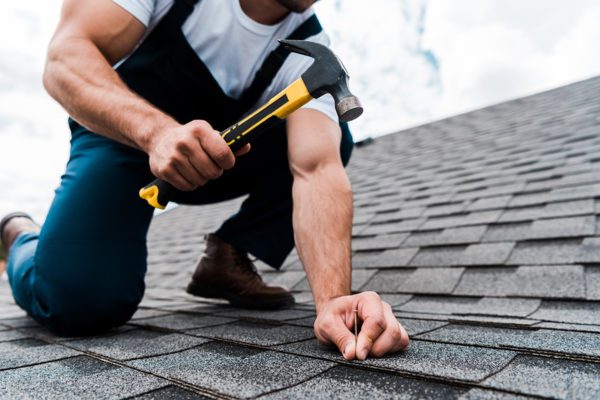 Roofer putting a nail into the roof