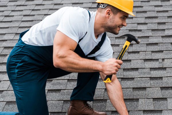 Smiling roofer on roof holding a hammer